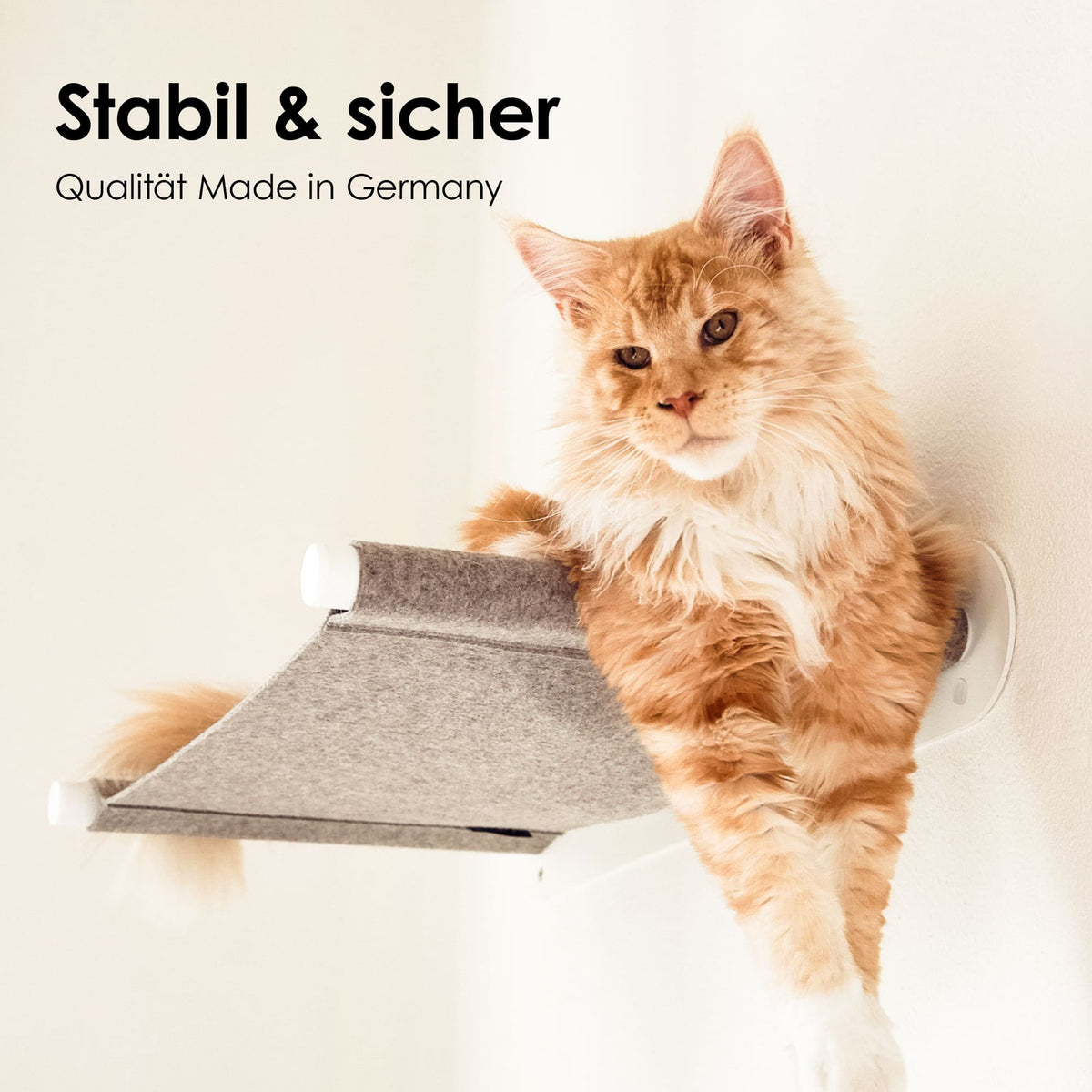 Große orangefarbene Katze liegt seitlich auf einer hellgrauen Wandhängematte mit weißen Wandhaltern – stabil & sicher.